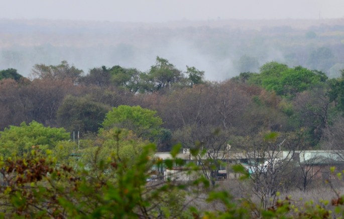 As nuvens de vapor vistas de Victoria Falls onde o "trovejar" é permanente